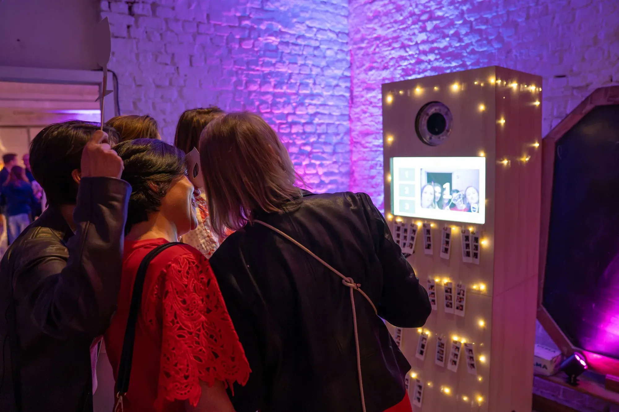 Guests posing with props in front of the Motion Box photo booth at a birthday party